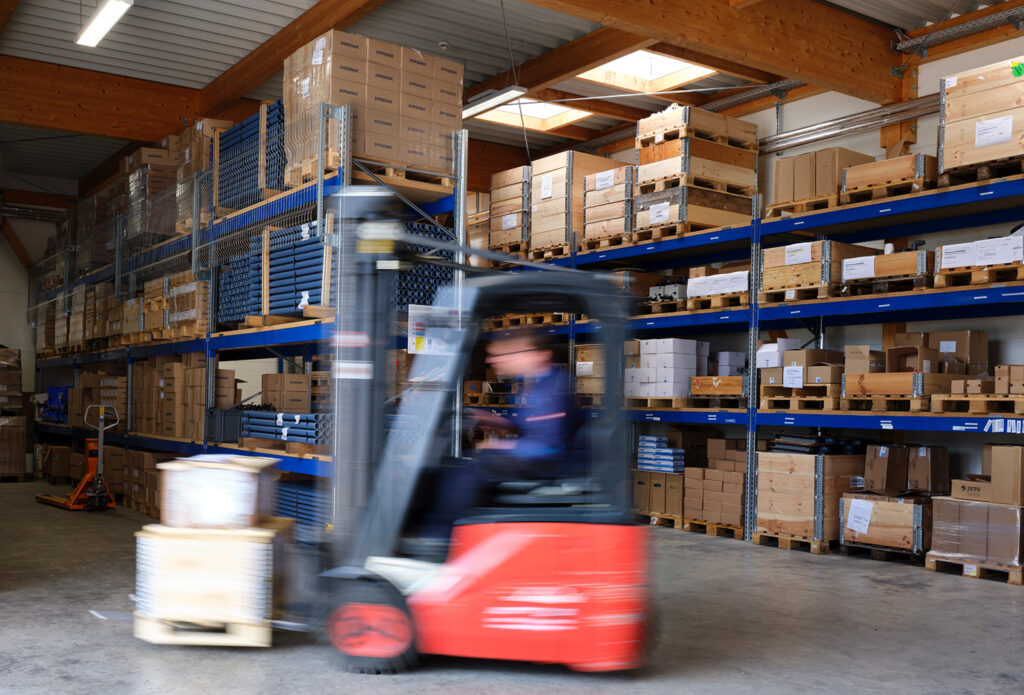 An SI Schiffstechnik employee is driving a forklift in the warehouse to pick up materials.